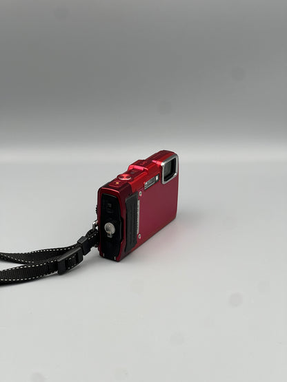 Angled front and side view of a red Olympus Stylus Tough TG-830 with its wrist strap attached