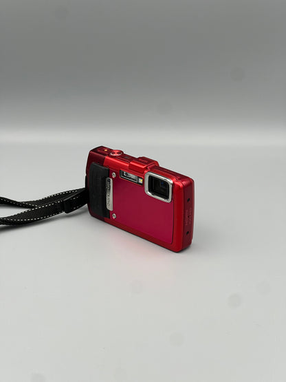 Angled front view of a red Olympus Stylus Tough TG-830 showing the lens, black grip and top controls