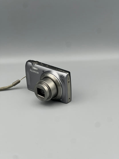 Front and side view of a silver Fujifilm FinePix T550 with its lens extended