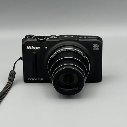 Black Nikon Coolpix S9700 front view with its zoom lens extended.