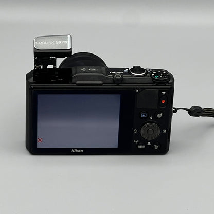 Nikon Coolpix S9700 rear view showing the LCD screen, controls and raised pop-up flash.