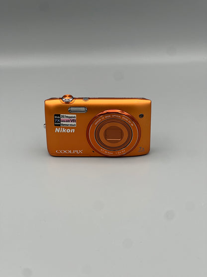Front view of an orange Nikon Coolpix S3500 with its lens closed