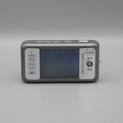 Rear view of a gray Kodak EasyShare V1003 showing the illuminated LCD screen and control buttons