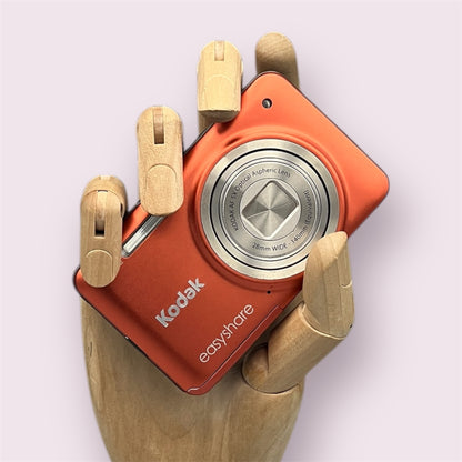 Orange Kodak EasyShare M5350 digital camera resting in a wooden hand with the lens closed
