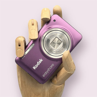Purple Kodak EasyShare M5350 digital camera resting in a wooden hand with the lens closed