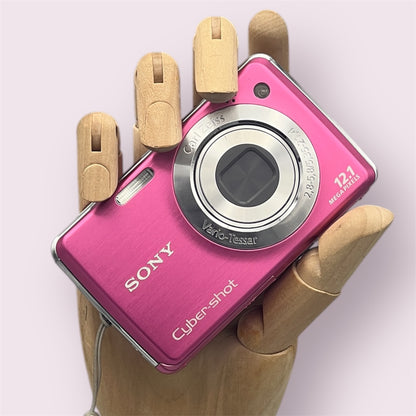 Pink Sony Cyber-shot DSC-W220 with its lens closed, held in a wooden display hand