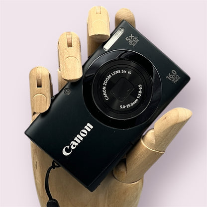 Black Canon PowerShot A3400 IS digital camera resting in a wooden hand with the front visible