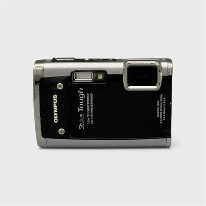 Front view of a black and silver Olympus Tough 6020 showing the exposed lens and flash
