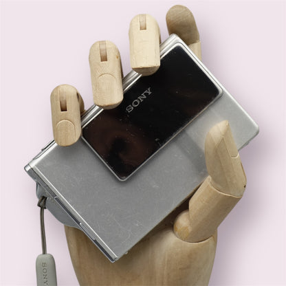 Silver Sony Cyber-shot DSC-T7 digital camera resting in a wooden hand with its sliding lens cover closed