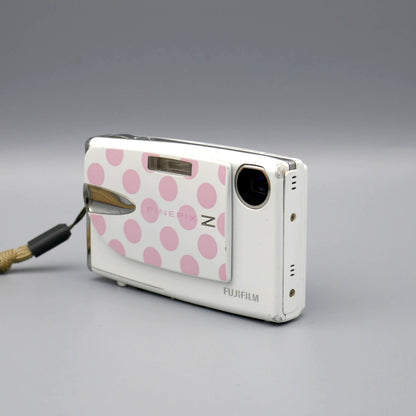 White Fujifilm FinePix Z20fd viewed from the opposite front corner with its pink polka-dot lens cover open
