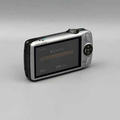 Angled rear view of a silver Canon PowerShot SD980 IS with a settings menu visible on its LCD screen