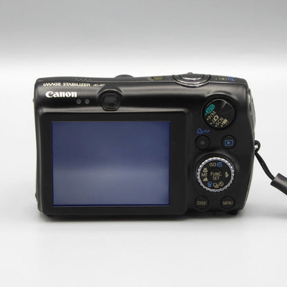 Rear view of a black Canon PowerShot SD990 IS showing the illuminated LCD screen and control buttons