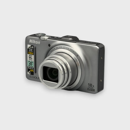 Front and side view of a silver Nikon Coolpix S9300 with its lens extended