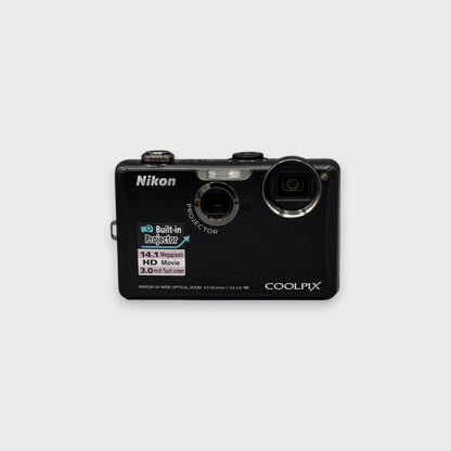 Front view of a black Nikon Coolpix S1100pj with its camera lens and built-in projector visible