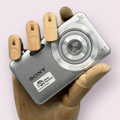 Silver Sony Cyber-shot DSC-W710 held in a wooden display hand with its lens closed.