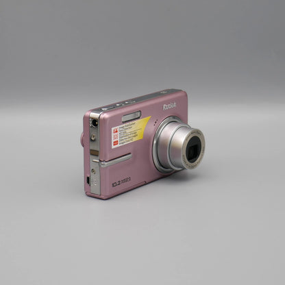 Pink Kodak EasyShare M1073 IS viewed from a front angle showing the extended lens and side panel.