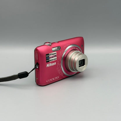 Angled front view of a pink Nikon Coolpix S3500 showing the extended lens and top controls