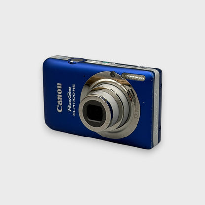 Blue Canon PowerShot ELPH 100 HS viewed from a front angle showing its extended lens and silver side panel.