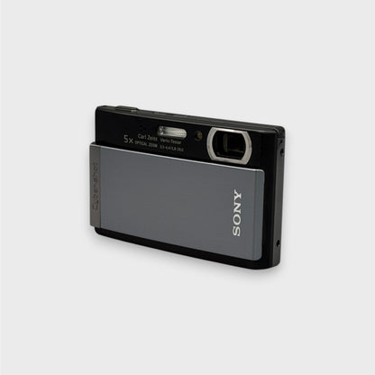 Front and side view of a gray and black Sony Cyber-shot DSC-T300 showing the exposed lens