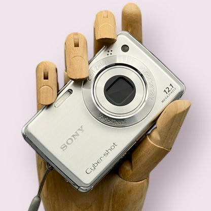 Silver Sony Cyber-shot DSC-W220 with its lens closed, held in a wooden display hand