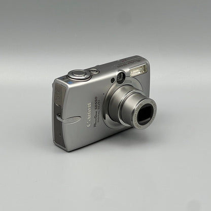 Silver Canon PowerShot SD550 viewed from a front angle with its lens extended and top controls visible.
