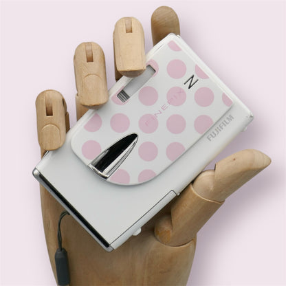 White Fujifilm FinePix Z20fd with a pink polka-dot lens cover, held in a wooden display hand