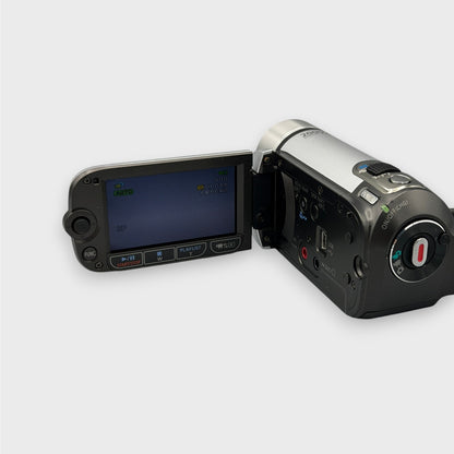 Canon FS200 camcorder with its LCD display lit, showing side controls and the rear record button