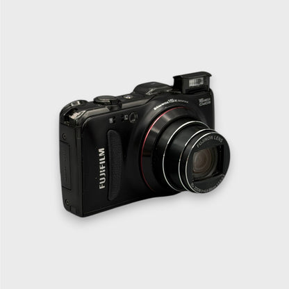 Black Fujifilm FinePix F550EXR viewed from a front angle with its zoom lens extended and flash raised.