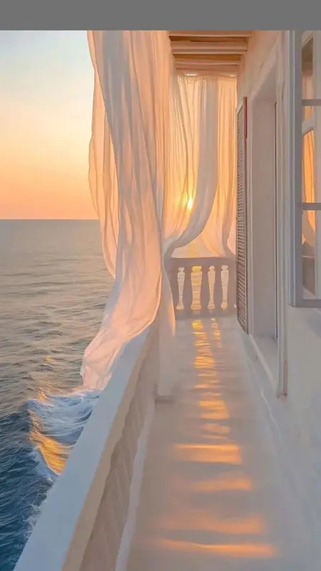 Soft evening light over a seaside balcony and billowing curtains