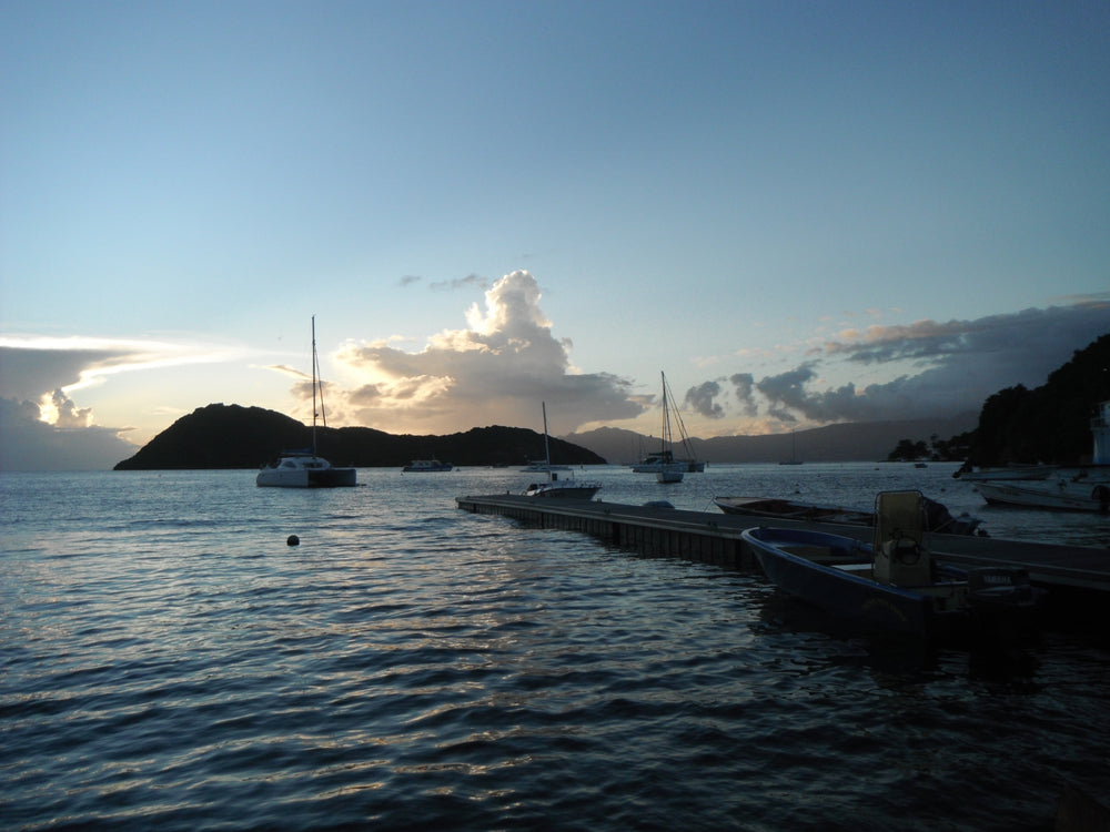 Sailboats and a jetty in a calm bay beneath a wide evening sky