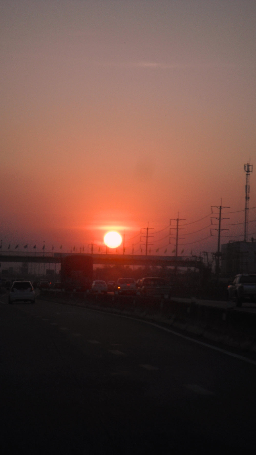 Orange sunset above road and power-line silhouettes